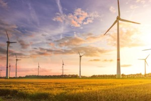 MULTIPLE WIND TURBINES STAND AGAINST A SUNSET SKY