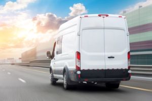 A DELIVERY VAN DRIVES DOWN THE HIGHWAY