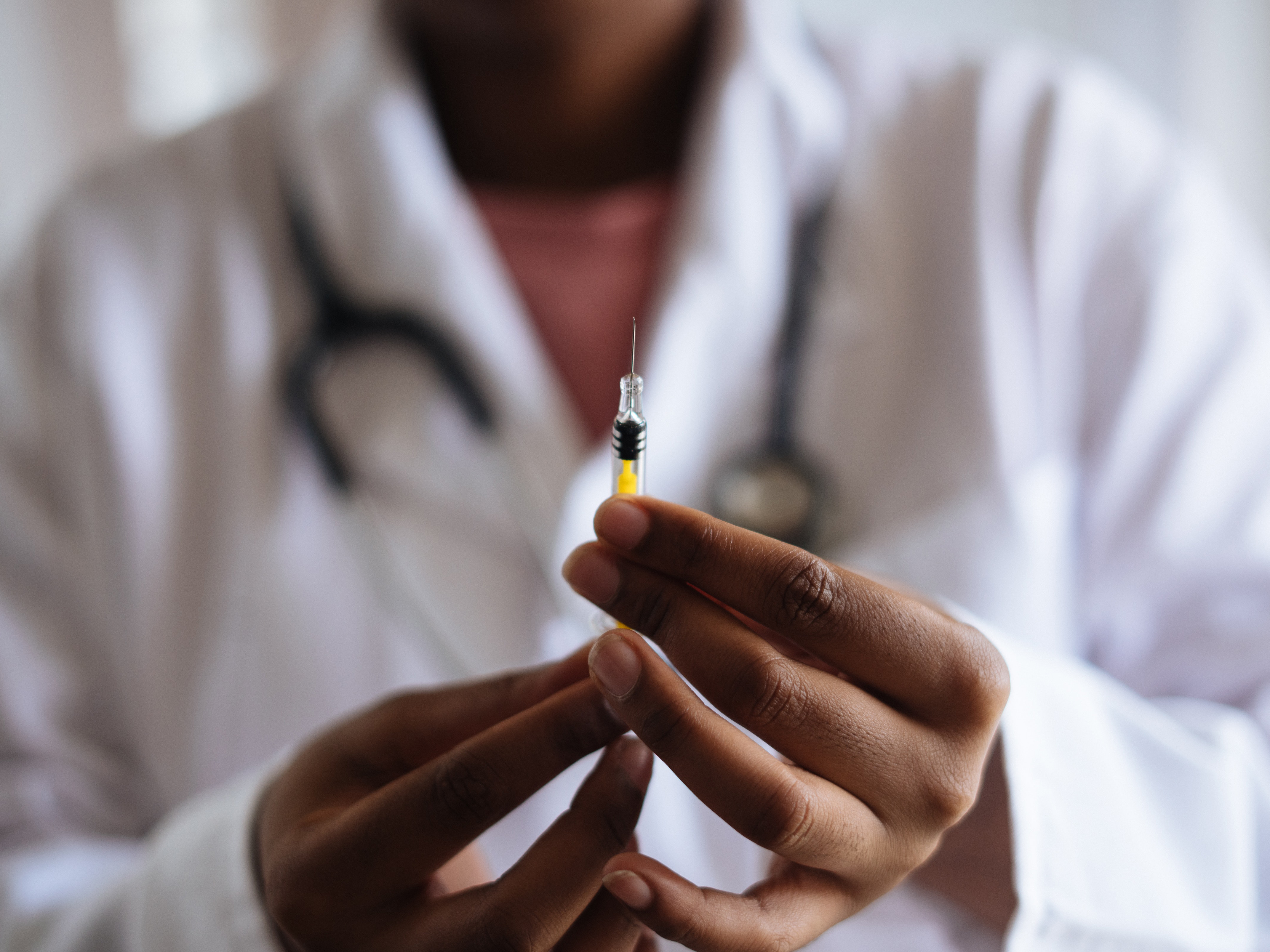 A doctor prepares a syringe for injection