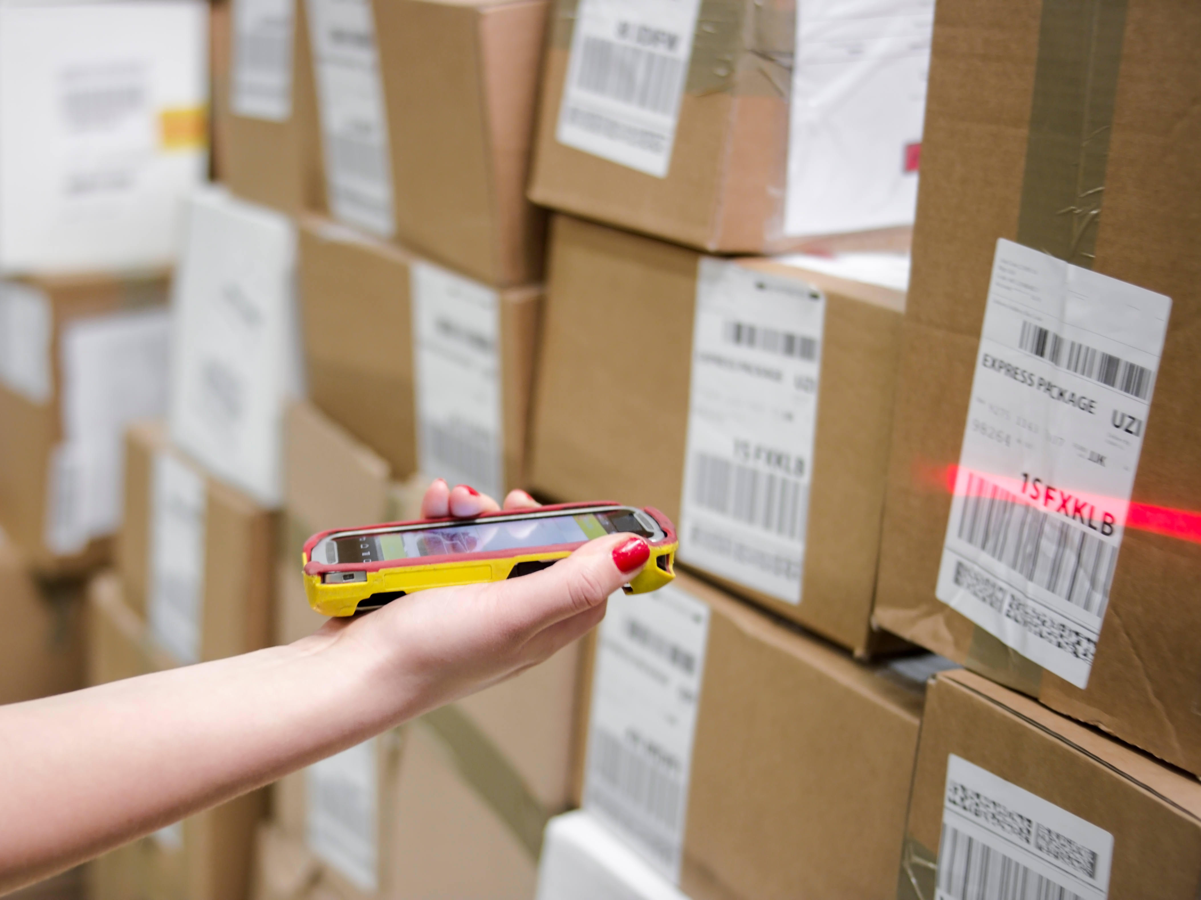 An employee uses a smartphone to scan shipping labels. 