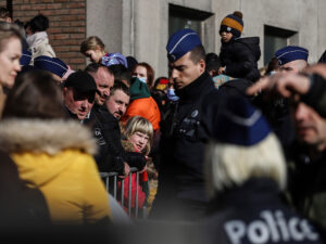 A UNIFORMED OFFICER STANDS IN A CROWD OF PEOPLE