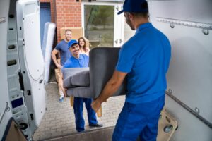 TWO MEN DELIVER A SOFA TO THE HOME OF A COUPLE