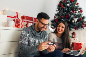 A MAN AND A WOMAN DELIGHTEDLY OPEN GIFTS IN FRONT OF A CHRISTMAS TREE968.jpg