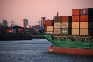 A CONTAINER SHIP ENTERS THE PORT OF HAMBURG AT SUNSET