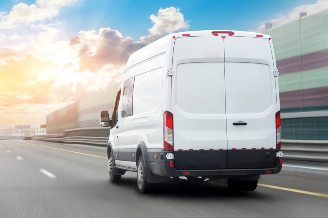 A DELIVERY VAN RUSHES DOWN A ROAD