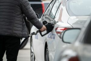 A PERSON PUMPS GAS INTO A CAR AT A GAS STATION