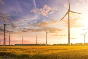 MULTIPLE WIND TURBINES STAND AGAINST A SUNSET SKY