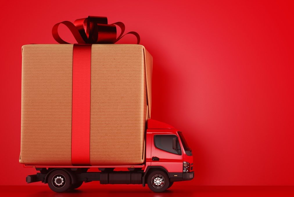 A TOY TRUCK CARRIES A GIANT BOX WITH A RED RIBBON IN A BOW