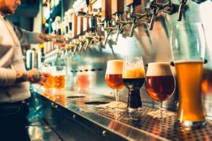 Side view of young bartender pouring beer while standing at the bar counter