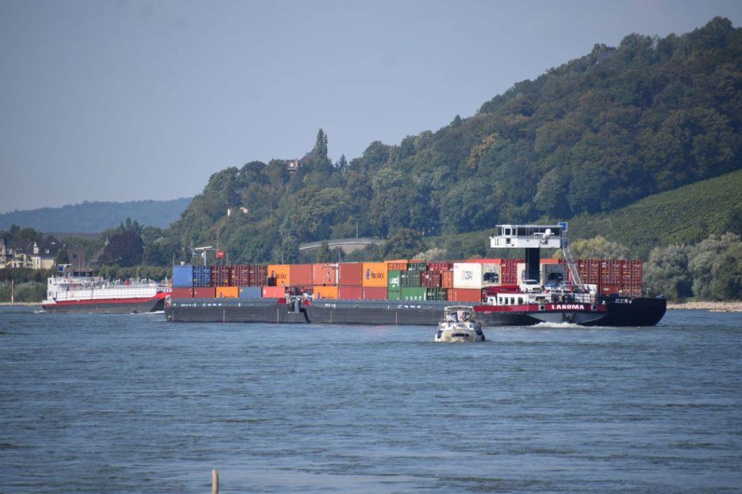 A CARGO SHIP NAVIGATES A WIDE RIVER BORDERED BY GREEN HILLS53.jpg