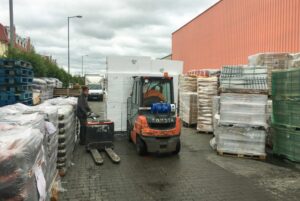 Two fork lifts pass each other unloading merchandise in an overcrowded storage area 