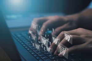 A PAIR OF HANDS TAPS ON A KEYBOARD, WITH IMAGES OF SHOPPING CARTS HOVERING JUST ABOVE