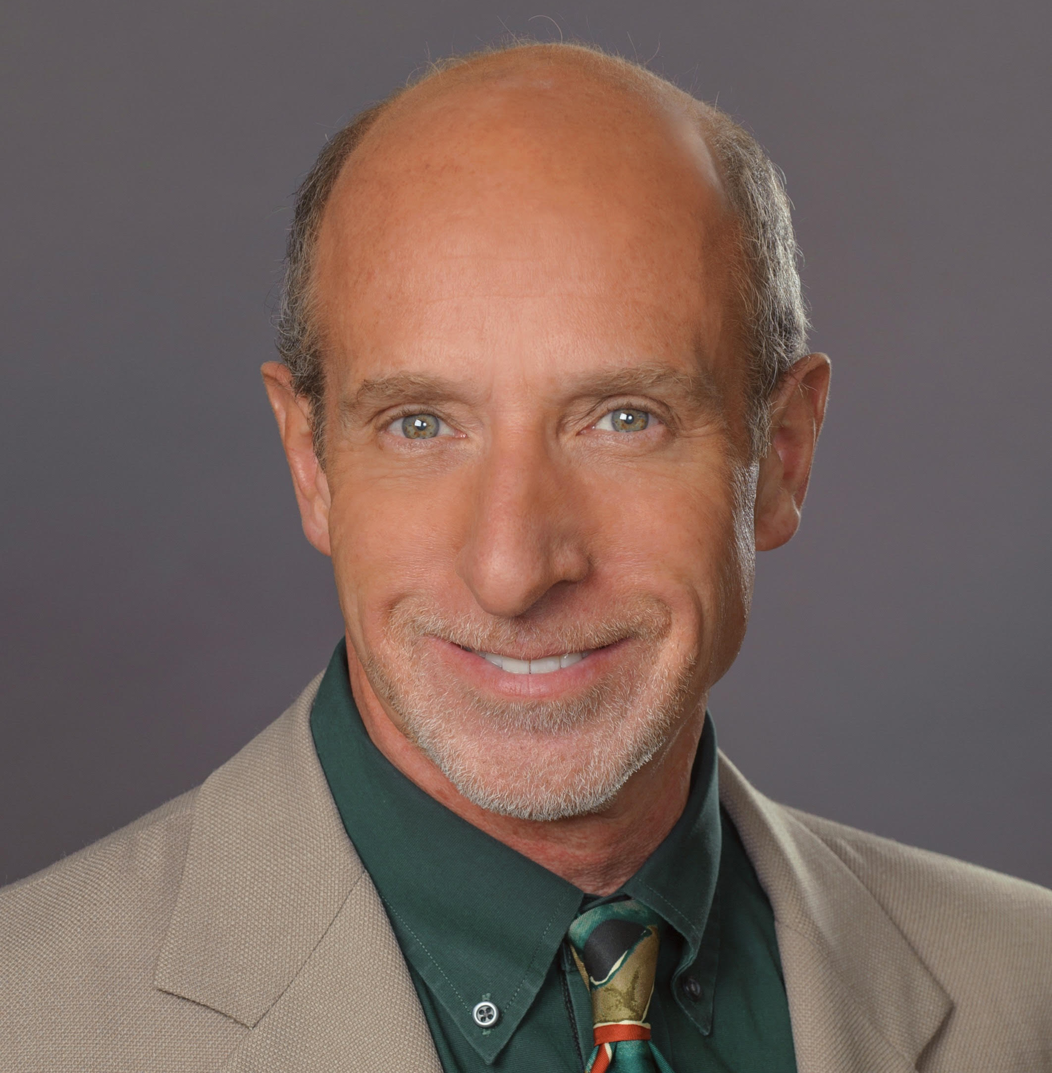  A HANDSOME MIDDLE-AGED MAN IN A JACKET AND TIE SMILES INTO THE CAMERA