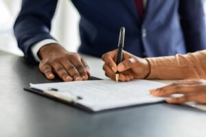 A CLOSE UP OF A SET OF HANDS SIGNING A CONTRACT.