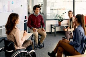 A multiracial group of business colleagues, one in a wheelchair, brainstorm during presentation in the office