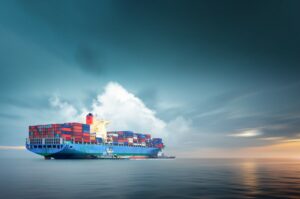 A CONTAINER SHIP PLIES THE OCEAN, SILHOUETTED BY DRAMATIC CLOUDS