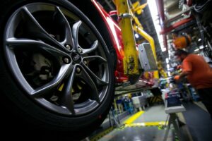 A CLOSE-UP OF THE TIRE OF A RED FORD VEHICLE IN A FACTORY.