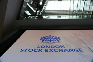 A GROUND VIEW LOOKING UP AT THE LOGO OF THE LONDON STOCK EXCHANGE CAN BE SEEN IN THE ATRIUM OF A LARGE BUILDING.