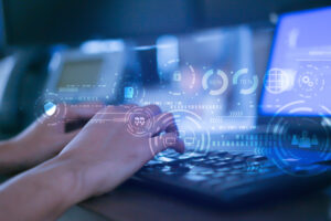 A CLOSE UP OF A PAIR OF HANDS TYPING ON A LAPTOP'S KEYBOARD WITH TRANSLUCENT LOCK AND SHIELD SYMBOLS FLOATING IN THE FOREGROUND.