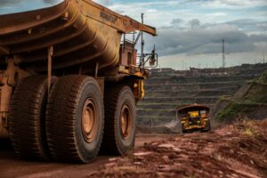 TWO YELLOW HAUL TRUCKS CAN BE SEEN WORKING IN AN IRON ORE MINE.