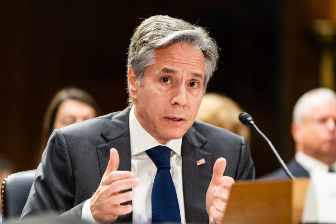 U.S. SECRETARY OF STATE ANTONY BLINKEN APPEARS TO BE SPEAKING IN FRONT OF A MICROPHONE.