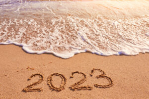 A WAVE APPROACHES A SANDY BEACH WITH THE NUMBER "2023" DRAWN IN THE SAND