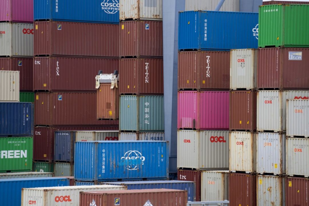 DOZENS OF DIFFERENT COLORED SHIPPING CONTAINERS ARE STACKED ON TOP OF EACH OTHER AT THE PORT OF LONG BEACH.