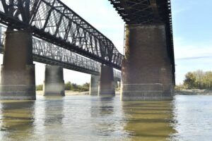 A METAL BRIDGE STRETCHES OVER A WIDE RIVER