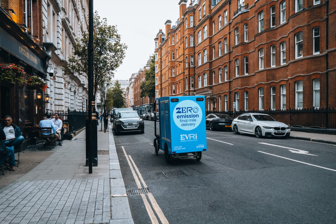 A SMALL BLUE EVRI CARGO DELIVERY BIKE IS ON THE STREETS OF A CITY.