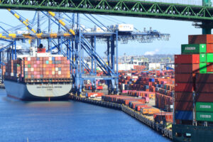 A LARGE CONTAINER SHIP IS DOCKED NEXT TO CRANES AT THE PORT OF LOS ANGELES.