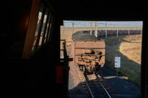 FREIGHT WAGONS LOADED WITH COAL APPEAR TO BE LEAVING A DARK TRAIN TERMINAL.