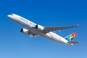 AN AIRPLANE WITH THE WORDS SOUTH AFRICAN ON THE SIDE AND A BRIGHTLY COLORED TAIL SHOWING ELEMENTS OF THE SOUTH AFRICAN FLAG, FLIES ACROSS THE SKY510.jpg