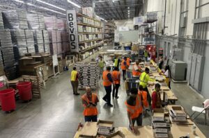 A BUSTLING WAREHOUSE FULL OF PEOPLE AND RACKS OF GOODS