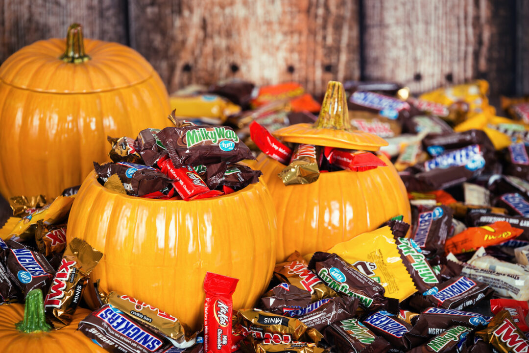 THREE DECORATIVE PUMPKINS ARE FILLED WITH AN ASSORTMENT OF CANDY AND ARE SURROUNDED BY MARS PRODUCTS.