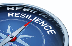 TOP PART OF A COMPASS WITH THE ARROW POINTING TOWARD THE WORD "RESILIENCE."