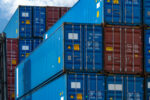 MIXTURE OF RED AND BLUE SHIPPING CONTAINERS UNDER A CLOUDY, BLUE SKY.