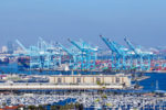 WIDE SHOT OF SEVERAL CRANES AND DOCKED BOATS AT THE PORT OF LOS ANGELES.