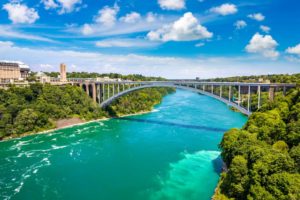 A SINGLE ARCH CONCRETE BRIDGE SPANS A BROAD RIVER