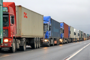 SEVERAL TRACTOR TRAILERS ARE LINED UP ONE AFTER ANOTHER ON A HIGHWAY.