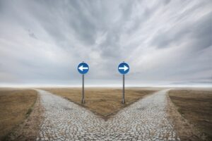 AT A FORK IN THE ROAD, TWO SIGNS POINT IN OPPOSITE DIRECTIONS