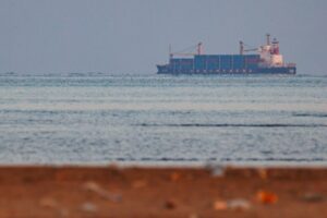 A CONTAINER SHIP AT SEA IS SEEN FROM THE SHORE