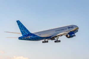 A LARGE JET TAKES OFF INTO A SILVER BLUE SKY