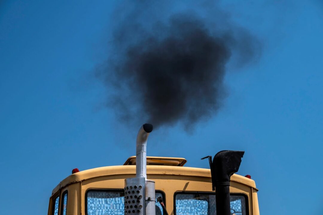 A TRUCK'S SMOKESTACK BELCHES BLACK SMOKE INTO A COBALT BLUE SKY