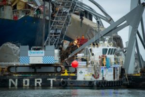 TANGLED WRECKAGE OF A BRIDGE AND SHIP FLOAT ON WATER