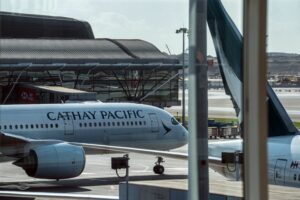 AN AEROPLANE BEARING THE CATHAY PACIFIC LOGO MOVES ACROSS THE TARMAC OF AN AIRPORT