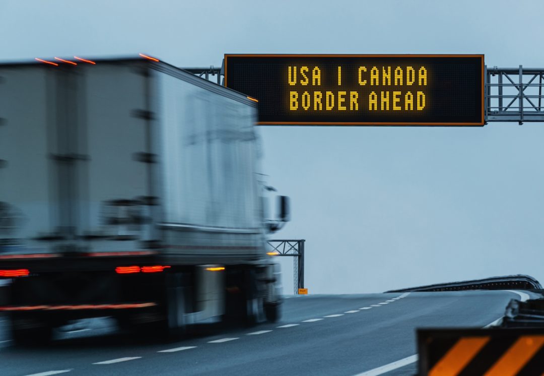 A semi truck approaching a "border ahead" highway sign.