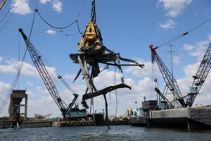 A CRANE LIFTS METAL DEBRIS OUT OF A RIVER