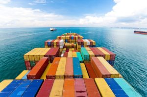 Horizontal wide angle view of heavy loaded container cargo ship in busy strait of Malacca