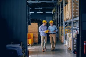 Two men in hard hats walking in a warehouse