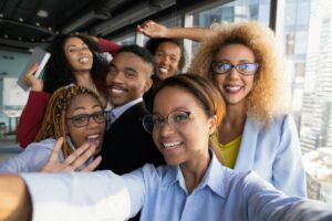 AN EXUBERANT GROUP OF YOUNG WORKERS POSE FOR AN OFFICE SELFIE